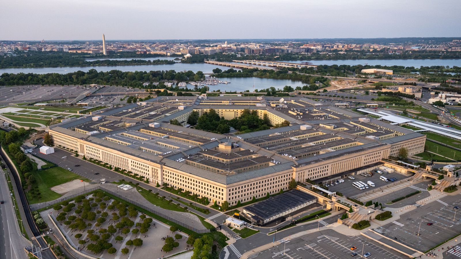 Aerial view of the Pentagon at golden hour, with the Potomac River and Washington, D.C. skyline behind it