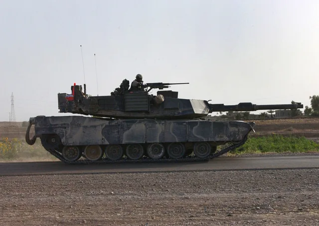 An M1A1 Abrams tank on a paved vehicle route.
