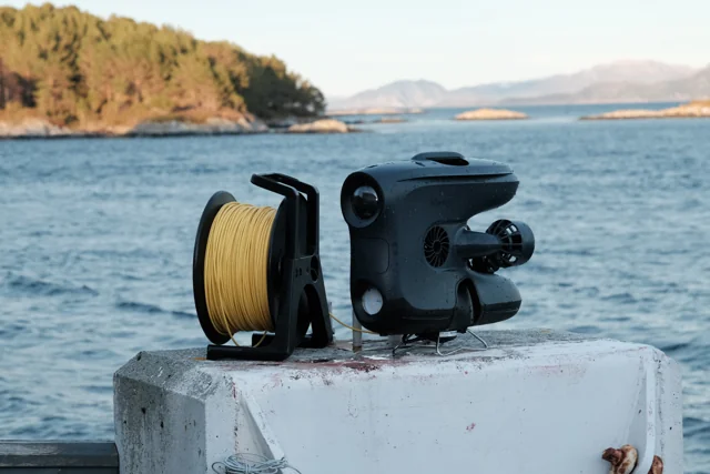 Blueye X3 Ultra underwater vehicle beside a fjord.
