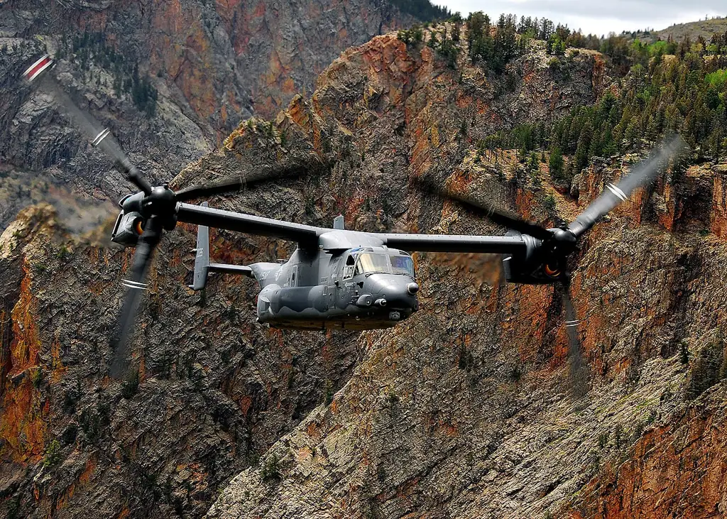 A CV-22 Osprey flying past rocky canyon walls