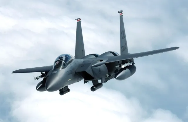 An F-15E Strike Eagle banking away over clouds after aerial refueling above the North Sea