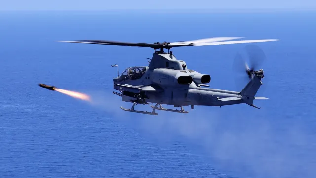 A Marine Corps AH-1Z Viper firing an AGM-179 JAGM over the sea off Okinawa