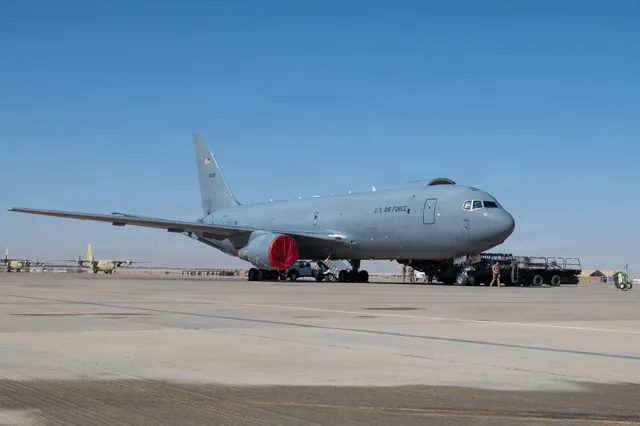 A KC-46A Pegasus tanker parked on an airfield with ground support equipment.