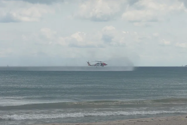 A U.S. Coast Guard MH-60T Jayhawk helicopter flying low over water