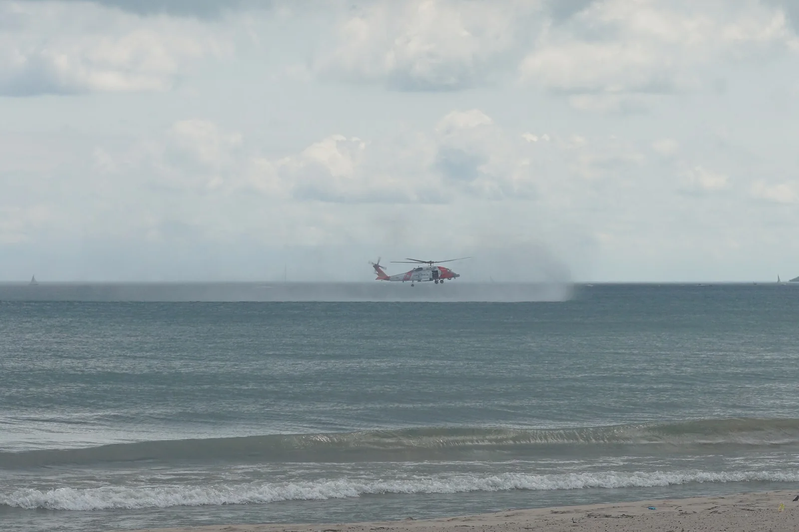 A U.S. Coast Guard MH-60T Jayhawk helicopter flying low over water