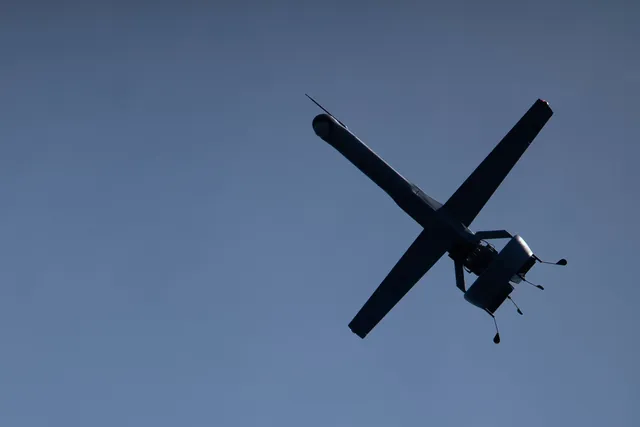 A V-BAT uncrewed aircraft in flight above USS Rushmore.